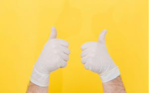 A person with white gloves showing thumbs up with both hands.