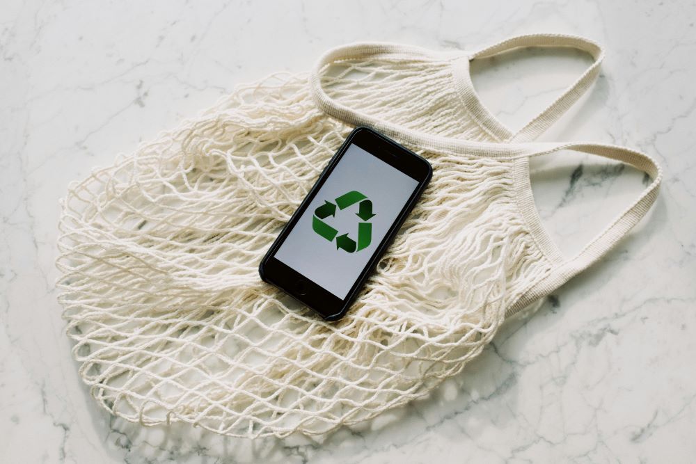 A mobile phone with a green recycling sign on a white bag