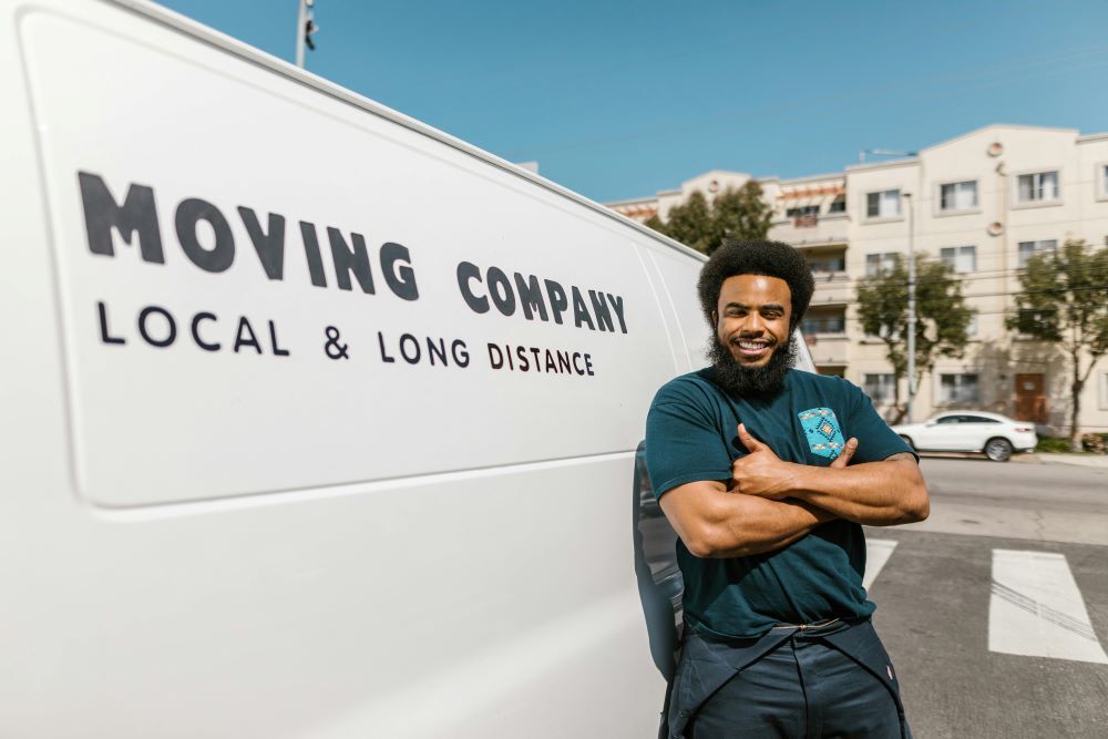  A man standing beside a white moving company van